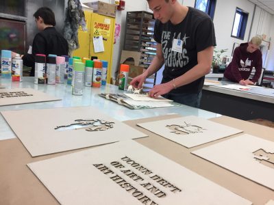 Prospective students making their own stencils and tote bags in the print shop for Spring into the Arts.
