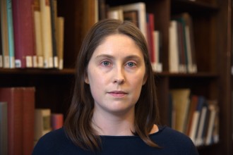 A photo of Kathryn Moore sitting in front of a bookshelf.